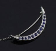 A white gold and sapphire crescent bar brooch, set with thirteen graduated round cut sapphires, with