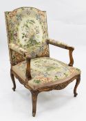 A Louis XVI style walnut open armchair, with floral tapestry upholstery and foliate scroll carved