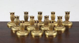 A set of twelve brass owl menu holders, each with purple cabochon eyes, on a circular base, 1.5in.