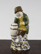 A Prattware figure of a young boy leaning on a barrel, late 18th century, wearing a hat, a green