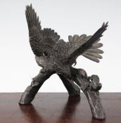 A Japanese bronze okimono of an eagle, Meiji period, perched on a branch to attack a monkey,