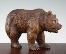 A Swiss Black Forest carved model of a standing bear, with glass eyes, 12in.