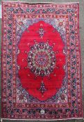 A Persian carpet, with large central medallion on a red ground with foliate angles and three row