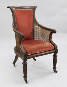 A Regency mahogany bergere library chair, with upholstered back and seat, caned sides with stiff