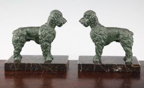 A pair of French Art Deco patinated metal bookends, modelled as poodles, on rectangular marble