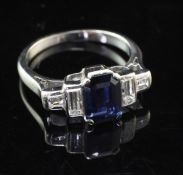 An early 20th century 18ct white gold, sapphire and diamond ring, the central emerald cut sapphire