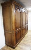 A large early 20th century French oak triple armoire, with three arched panelled doors carved with