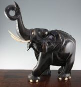 A large Indian ebonised carved hardwood elephant, with ivory tusks, and trunk raised, 21in.