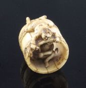 A Japanese ivory netsuke of two men constructing a barrel, Meiji period, one man lying on top of the