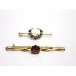 A SEVEN STONE SAPPHIRE CRESCENT BAR BROOCH with a single stone garnet bar brooch