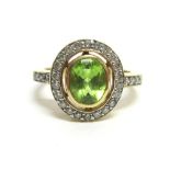 A PERIDOT AND DIAMOND CLUSTER 18CT GOLD RING the oval cut stone enclosed by twenty two brilliant cut