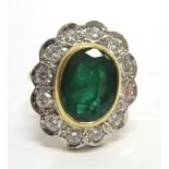 AN EMERALD AND DIAMOND 18CT GOLD CLUSTER RING the oval cut stone enclosed by twelve brilliant cut