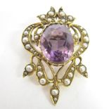 AN AMETHYST AND SEED PEARL BROOCH circa 1905, stamped '15ct', the oval cut within a scrolling seed