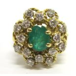 AN EMERALD AND DIAMOND CLUSTER RING apparently unmarked, the oval cut emerald, 6.8mm by 5.2mm