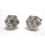 A PAIR OF SEVEN STONE DIAMOND CLUSTER EARSTUDS in unmarked white metal, the fourteen brilliant