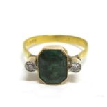 A DIAMOND AND GREEN STONE RING the step cut stone on a closed back setting flanked either side by