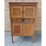 AN OAK SIDE CABINET with carved decoration to the drawer, fitted with cupboards above and below,