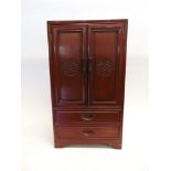 A SMALL ORIENTAL CARVED HARDWOOD CABINET fitted with two drawers beneath cupboard, 40.5cm wide