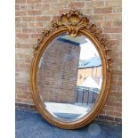A LARGE LATE VICTORIAN OVAL GILT GESSO FRAMED WALL MIRROR with foliate decoration and bevel edged