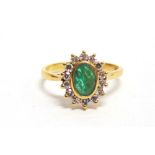 AN EMERALD AND DIAMOND 18 CARAT GOLD CLUSTER RING the oval cut stone enclosed by seven single cut