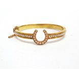 A VICTORIAN SEED PEARL AND CORAL HINGED GOLD BANGLE unmarked, the horse shoe coral set motif between