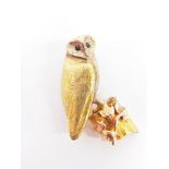 A REALISTICALLY MODELLED THREE COLOUR 9 CARAT GOLD OWL BROOCH with sapphire set eyes, standing on an