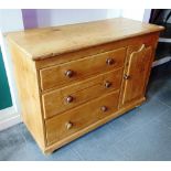 A STRIPPED PINE CUPBOARD,  fitted with three graduated long drawers and cupboard on bun feet,