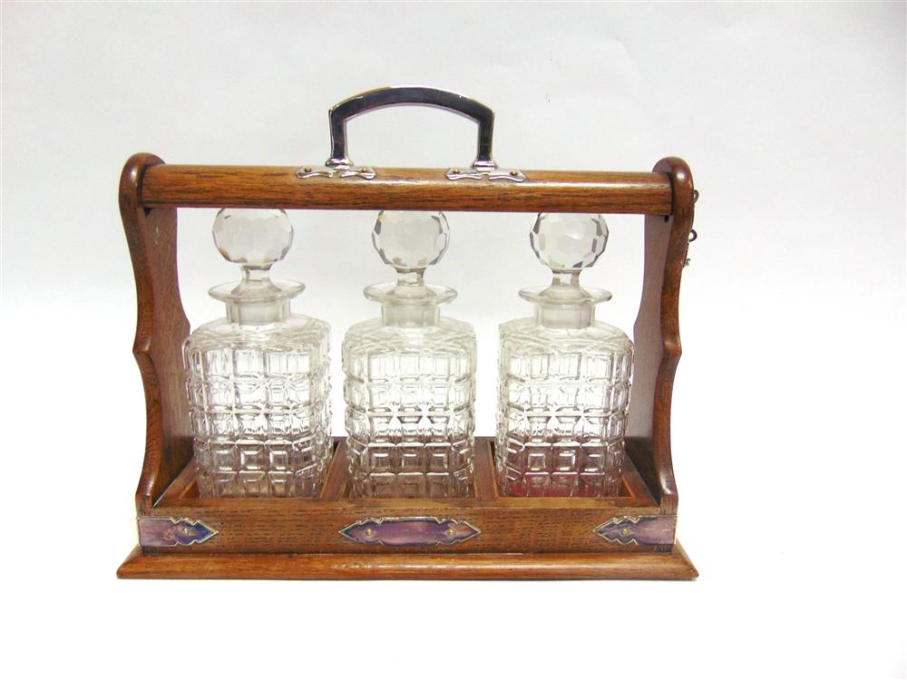 AN EDWARDIAN THREE BOTTLE EP MOUNTED OAK FRAMED TANTALUS,  with two keys, 32cm high including