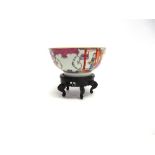 A CHINESE FAMILLE ROSE BOWL decorated in enamels with figures in a garden setting before a shore,
