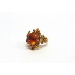 A 9 CARAT GOLD CITRINE DRESS RING maker H.B., London 1969, the oval cut stone to a textural random