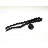 A JET BEAD NECKLACE the graduated carved beads 64cm long; with a jet cameo brooch