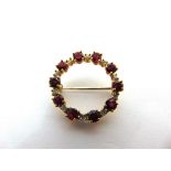 A RUBY AND DIAMOND CIRCLET BROOCH tagged '18ct', the ten oval cut stones with a small brilliant