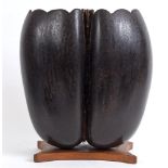 A COCO-DE-MER the top cut and shaped to create a vase, mounted on a wooden base, overall 31cm high.