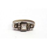 A DIAMOND RING the central square cut diamond of approximately 0.4 carats, flanked either side by