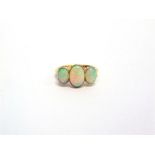 A THREE STONE OPAL RING stamped '18ct' and 'Plat', the graduated oval cabochons millegrain set,