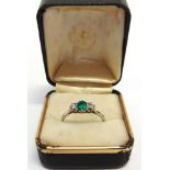 A DIAMOND AND EMERALD THREE STONE RING the step cut stone flanked by brilliant cuts totalling