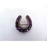 A LATE VICTORIAN AMETHYST AND DIAMOND HORSE SHOE BROOCH the fifteen graduated oval cuts with rose