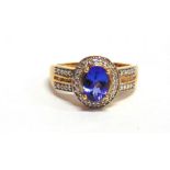 A TANZANITE AND DIAMOND 18 CARAT GOLD RING the oval cut stone twenty four small brilliant cuts