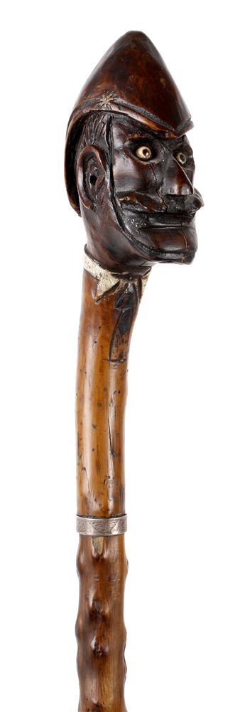 ANGLO-ZULU WAR 1879 - AN UNUSUAL CARVED WALKING CANE  the grip modelled as the head of a moustached,