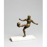 A small spelter figure of a footballer, bronze patina, modelled volleying the ball, set on a