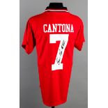 A red No.7 football jersey signed by Eric Cantona,
signed on the reverse No.