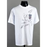 A white t-style football shirt signed by eight England legends,
comprising: Gary Lineker,