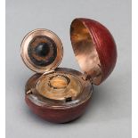 A Victorian travelling inkwell modelled as a cricket ball,
with a red leather covering,