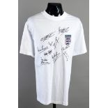 A white t-style football shirt signed by nine England legends,
comprising: Gary Lineker,