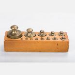 A Set of Thirteen Brass Weights in a Hardwood Block, 20th Century. The largest weight weighs 1Kg (