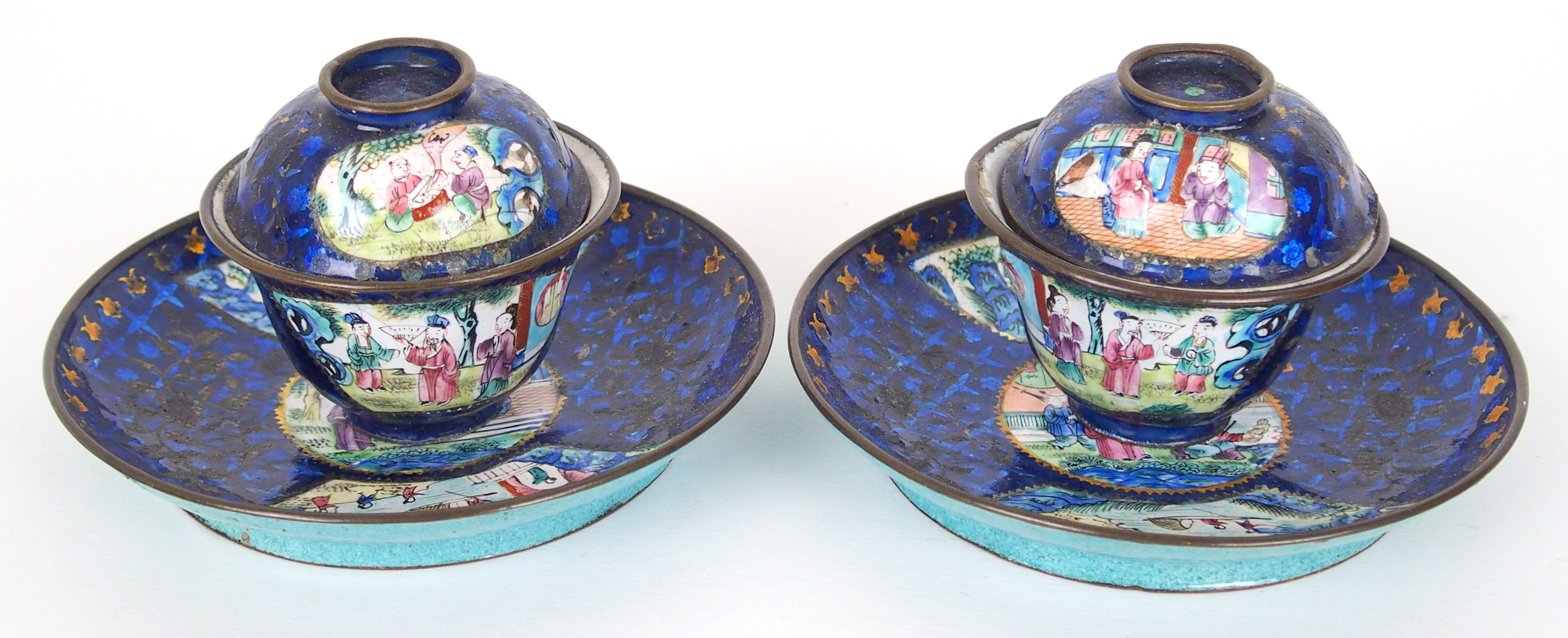 A pair of Canton enamel teabowls covers and saucers painted with figures on balconies on a blue