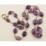 An amethyst bead necklace interspaced with yellow metal beads, indistinctly hallmarked to the clasp.