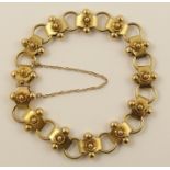 A late Victorian bracelet in yellow metal beaded units are embellished with a three dimensional