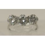 A substantial three stone diamond ring set throughout in 18ct white gold, the central diamond of