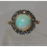 An opal and diamond ring the cabouchon opal is surrounded with rose cut diamonds, in yellow and